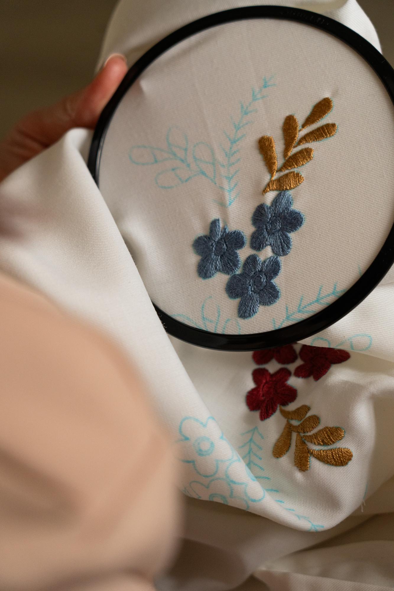 Close-up of hand embroidering a floral motif on linen